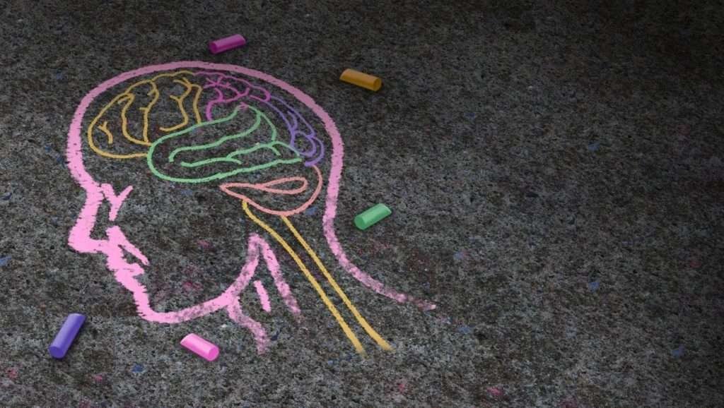 Pink chalk head in profile with multicoloured chalk brain on bitumen
