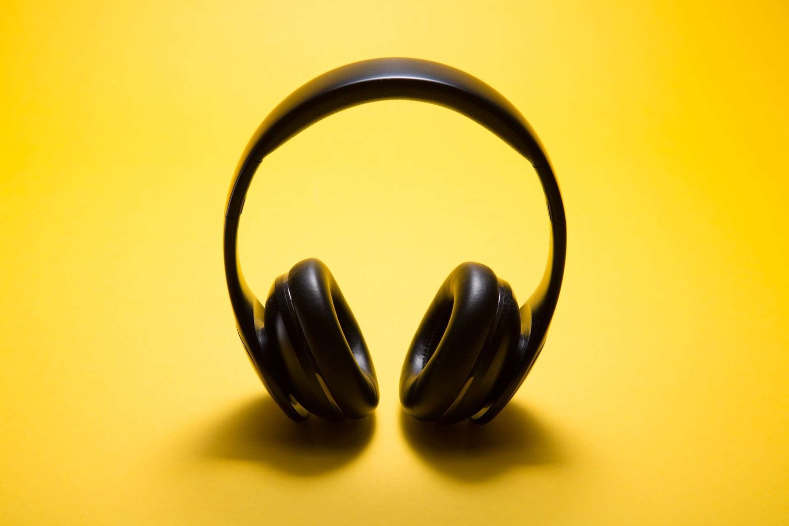 Black over ear headphones on yellow background